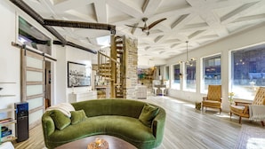 A spacious living area with a green sofa, wooden coffee table, and a spiral staircase. - Walk to Beaver Lake! 'the Cavehouse' w/ 4 Decks (Garfield)