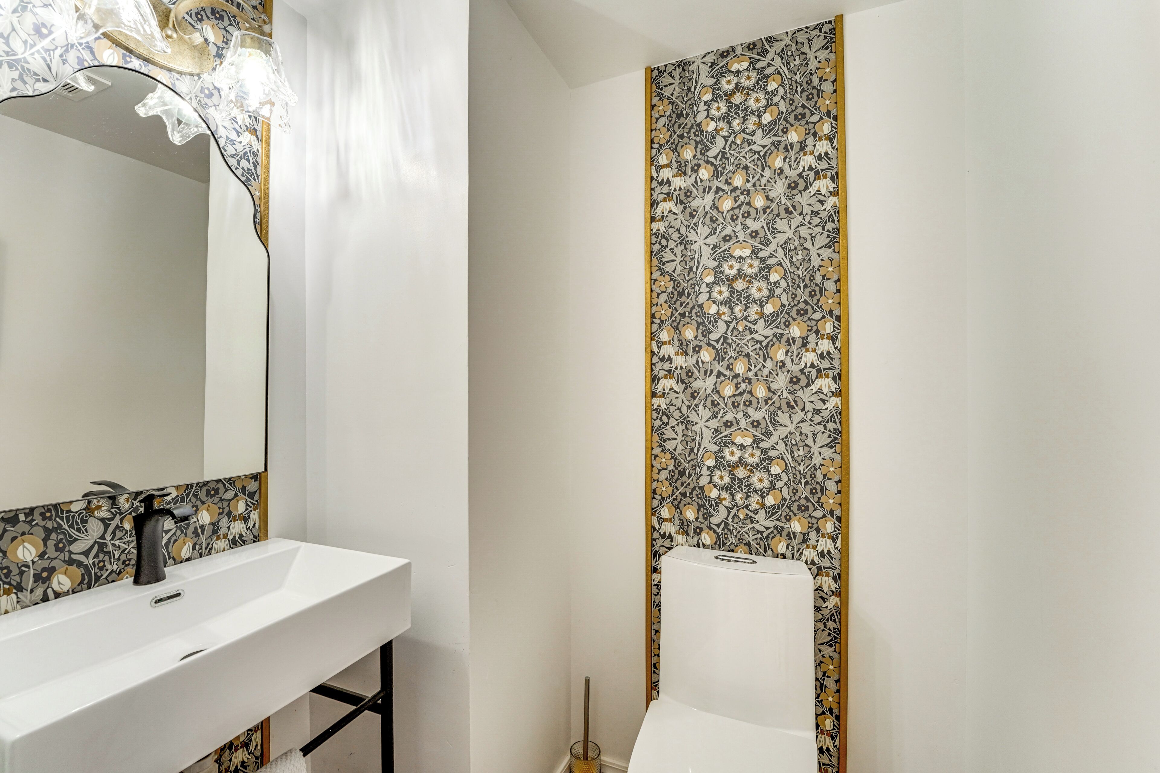 Un baño con lavamanos blanco, espejo y retrete.