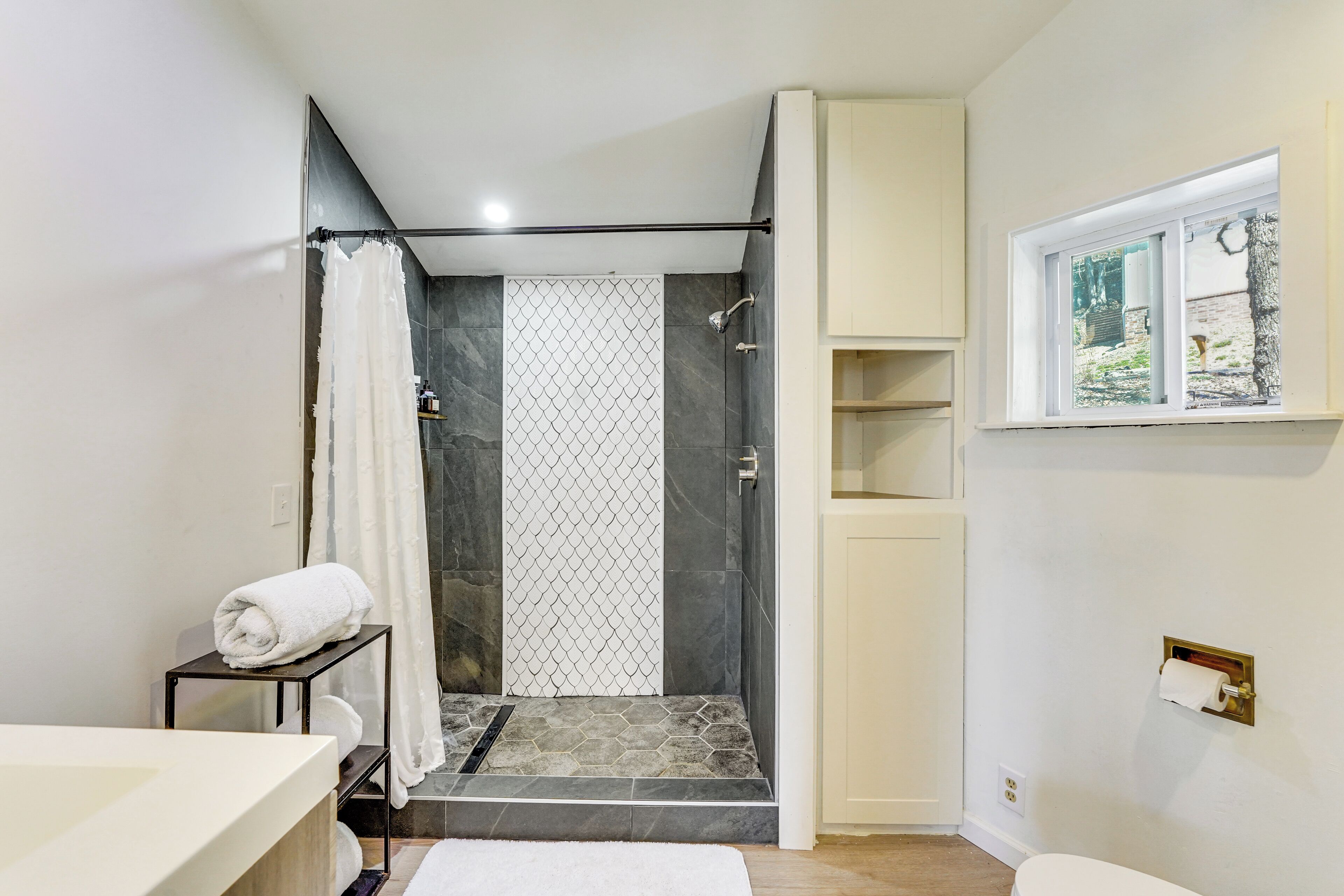 Et moderne badeværelse med bruser, toilet og vask.