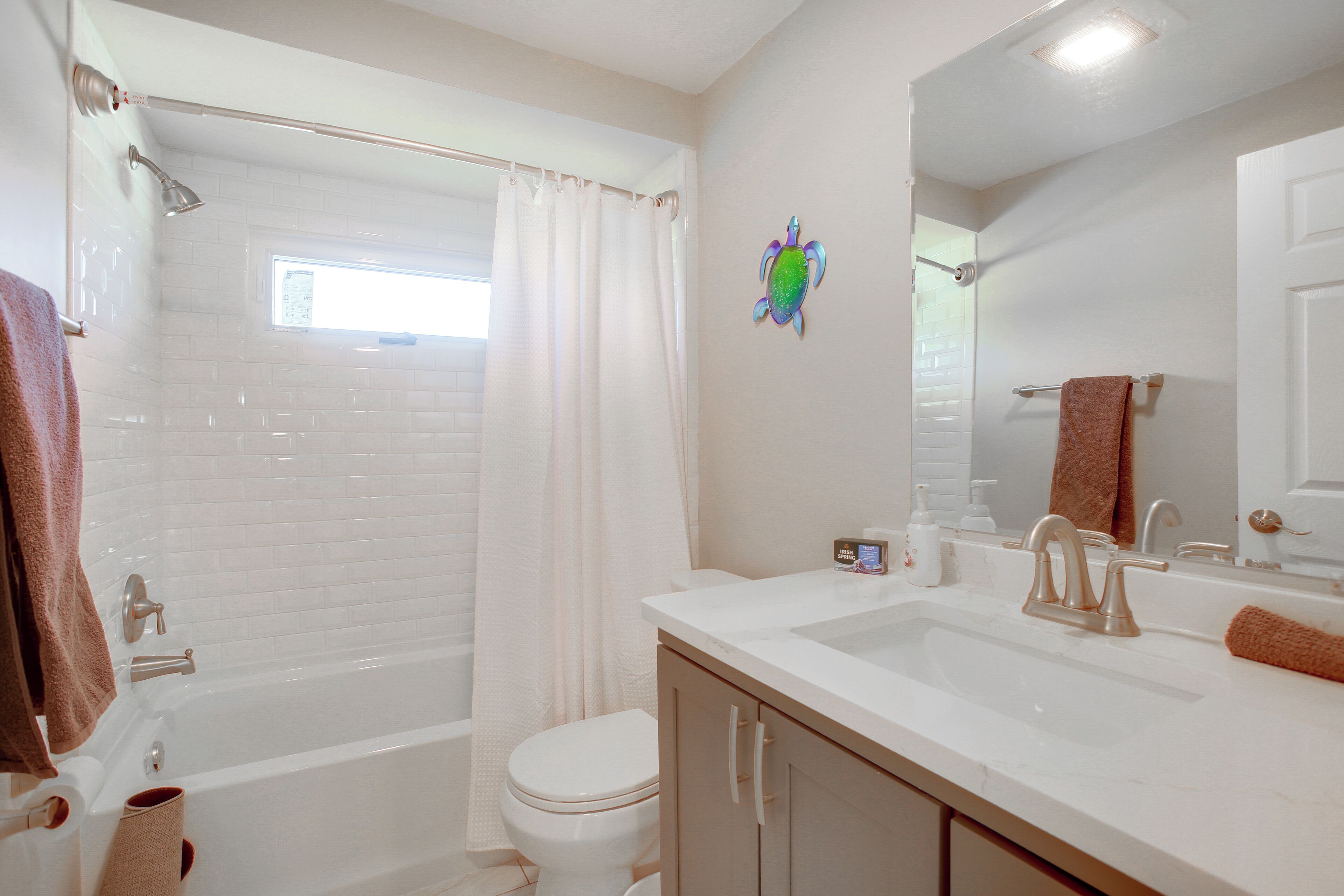 A bathroom with a bathtub, toilet, sink, and a mirror.