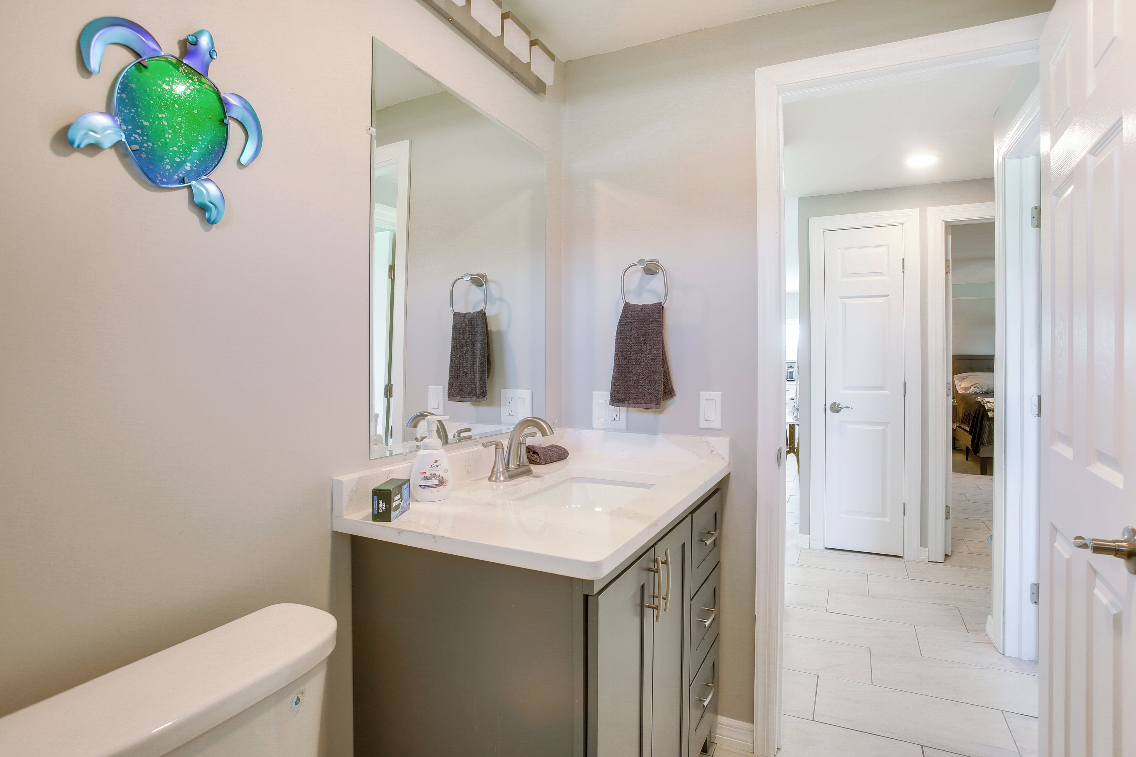 A bathroom with a toilet, sink, mirror, and a decorative turtle.