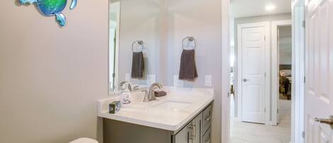 A bathroom with a toilet, sink, mirror, and a decorative turtle.