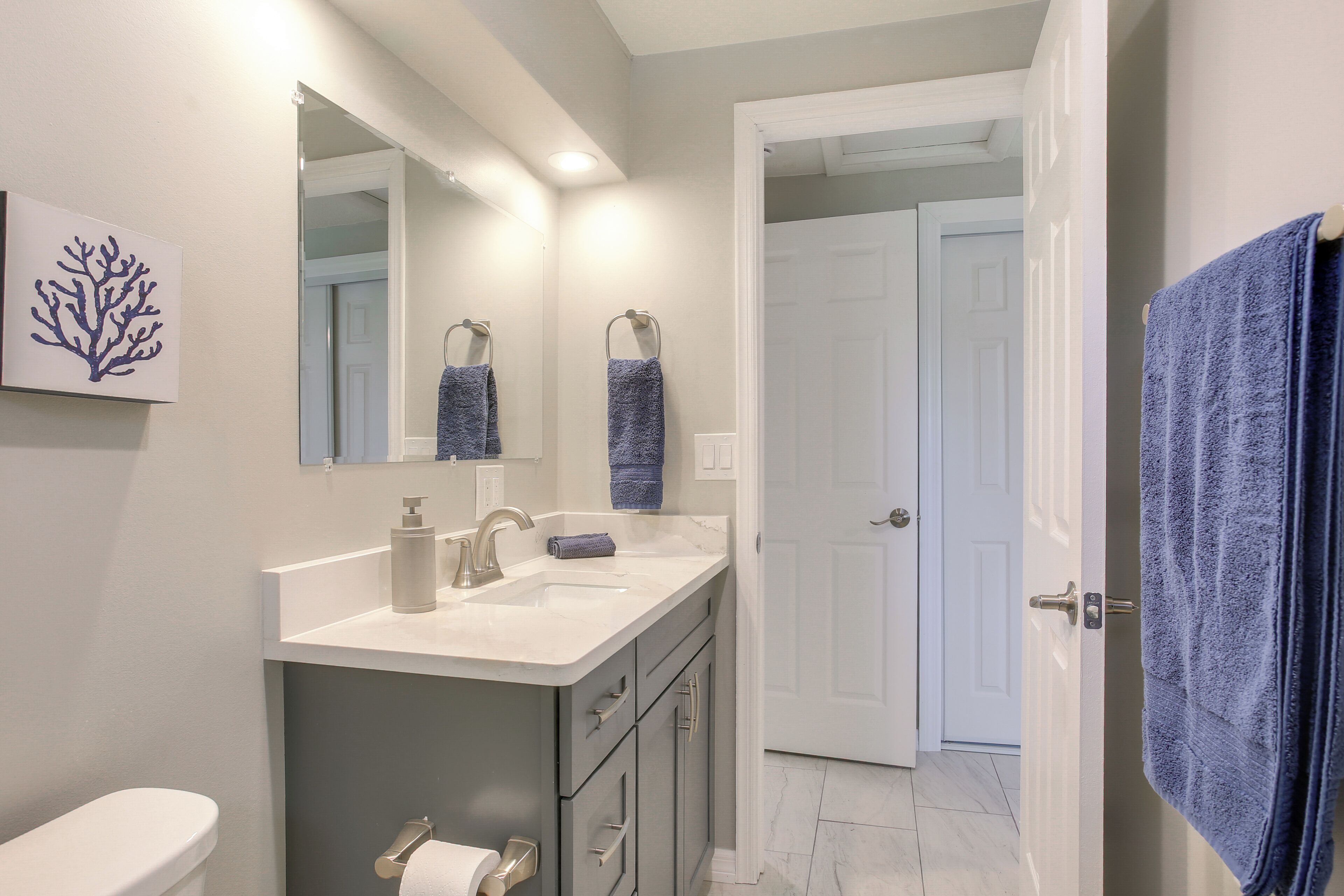 Une salle de bain équipée de toilettes, d’un lavabo, d’un miroir et d’un porte-serviettes.