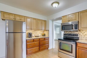 A kitchen with wooden cabinets, stainless steel appliances, and a tiled backsplash. - Sandusky Adventure Hub: Patios, Grill + Yard! (Sandusky)