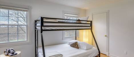 Ein Schlafzimmer mit Etagenbett, Fenster, Nachttisch und Tür.