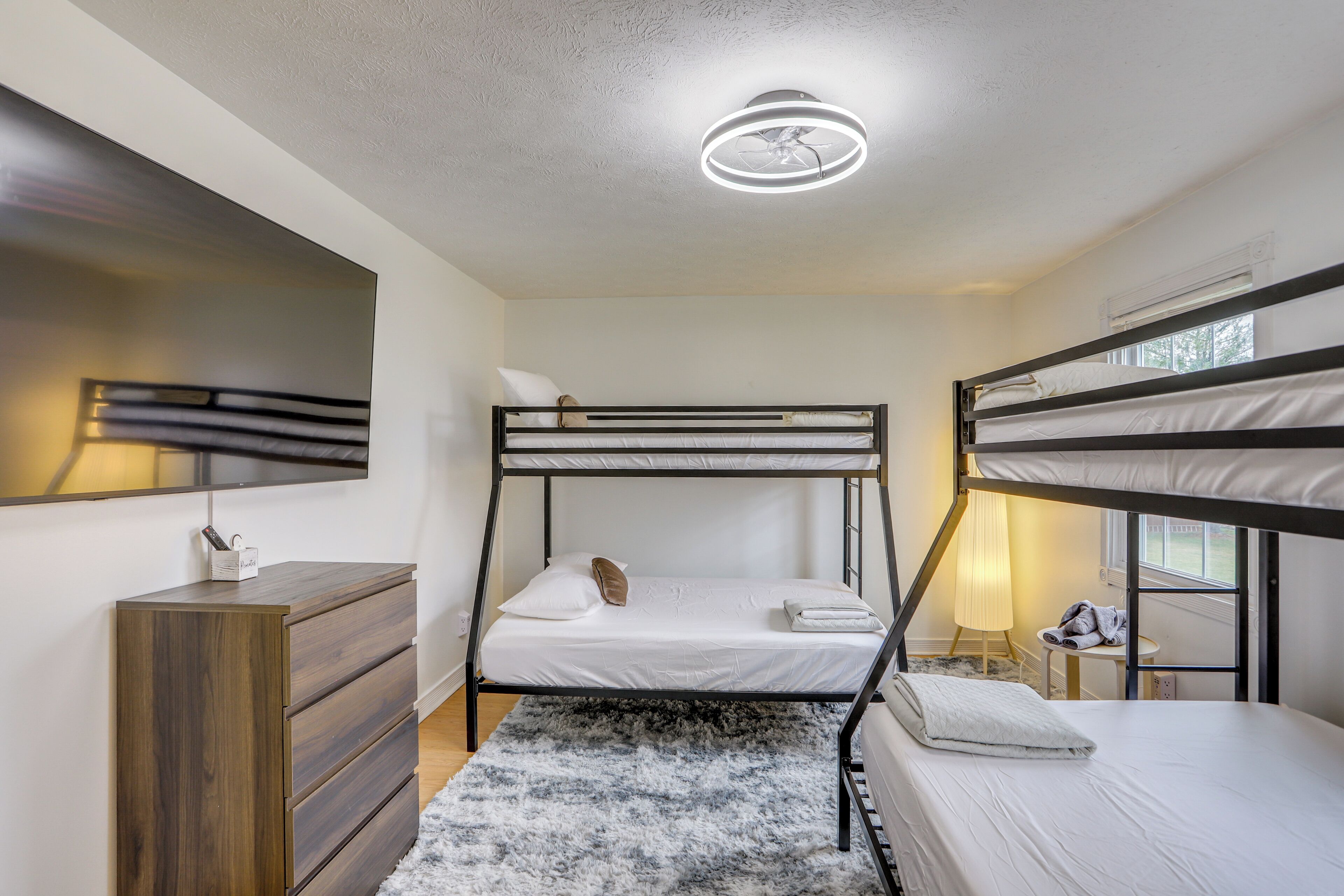 A bunk bed room with a desk, a mirror, and a ceiling light.