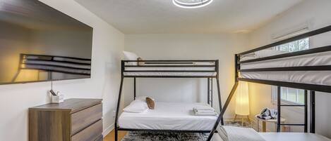 A bunk bed room with a desk, a mirror, and a ceiling light.