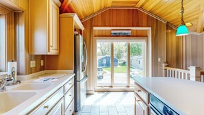 A kitchen with wooden paneling, a refrigerator, a sink, and a window with a view of the outside. - The Boat House w/ Dock: Enjoy Lake Life! (Syracuse)