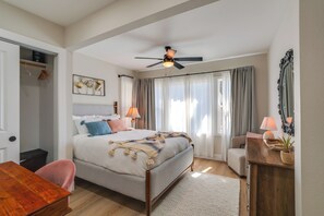 A bedroom with a bed, bedside table, chair, and a ceiling fan.
