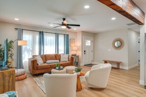 A living room with a brown sofa, white armchairs, a wooden coffee table, and a ceiling fan. - Downtown Modesto Gem! Updated Family Home (Modesto)