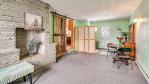 A room with a stone fireplace, a bench, a dining table with chairs, and a peacock decoration.