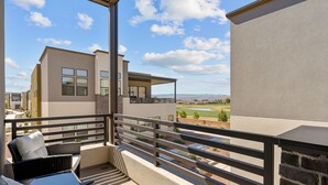 A balcony with wicker furniture, a view of neighboring buildings, and a clear sky. - Villa #44 at Bloomington Country Club: Pool, Golf, Restaurant (St. George)