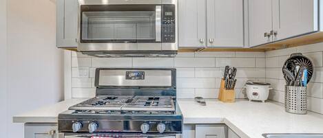 Una cocina equipada con estufa, horno, microondas y tostadora de acero inoxidable.