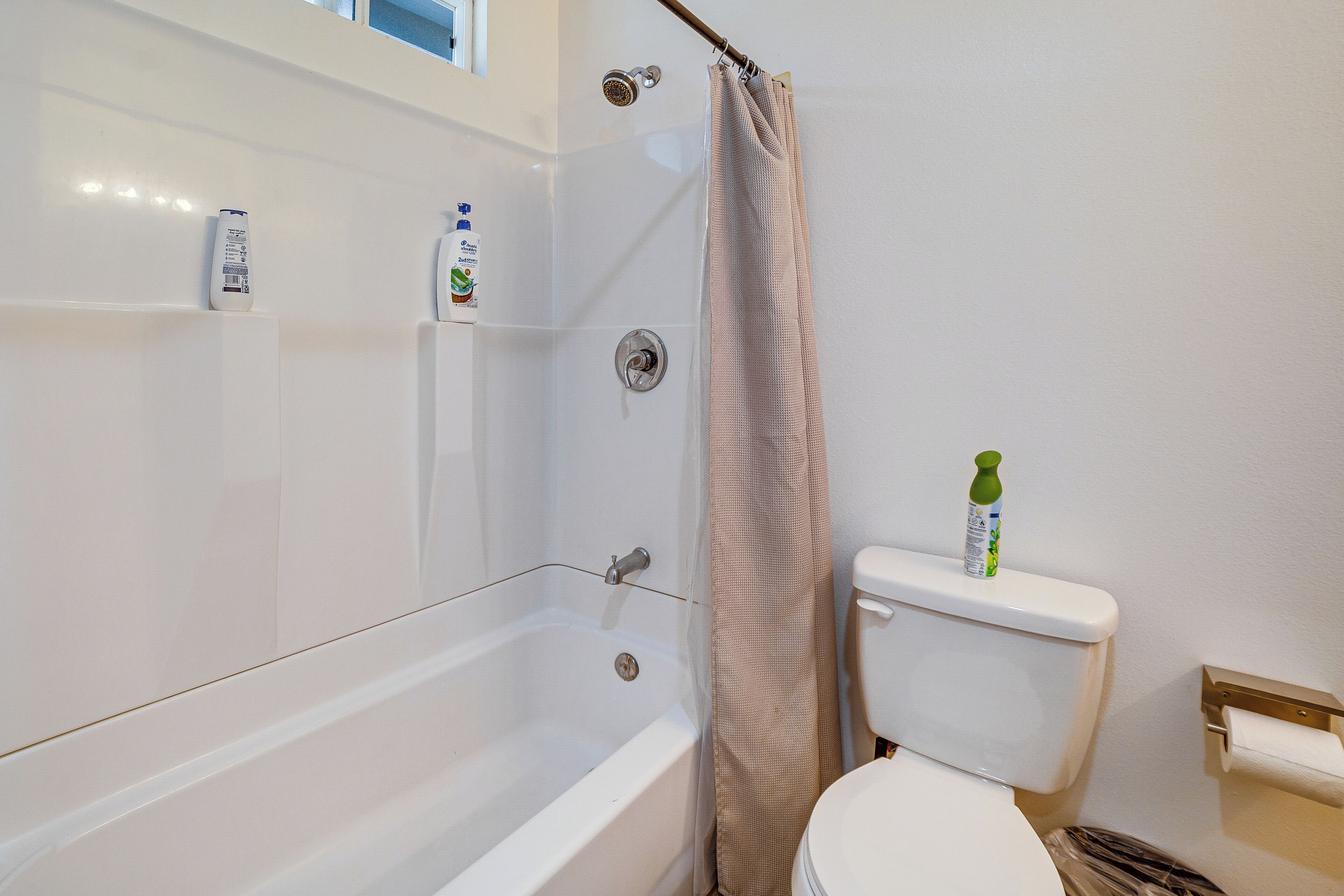 Et badeværelse med badekar, toilet og bruser.
