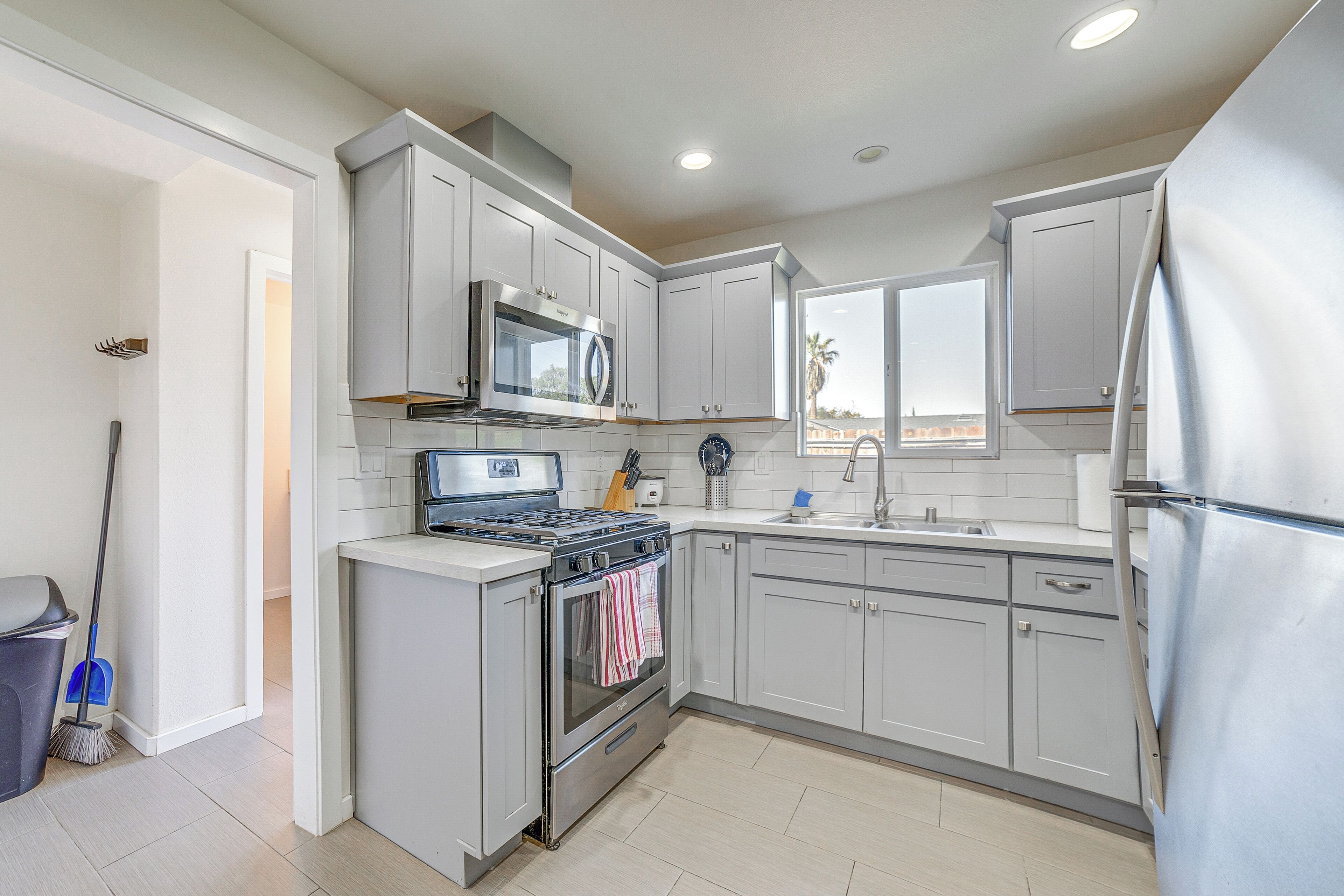 A modern kitchen with stainless steel appliances, white cabinetry, and a visible window.