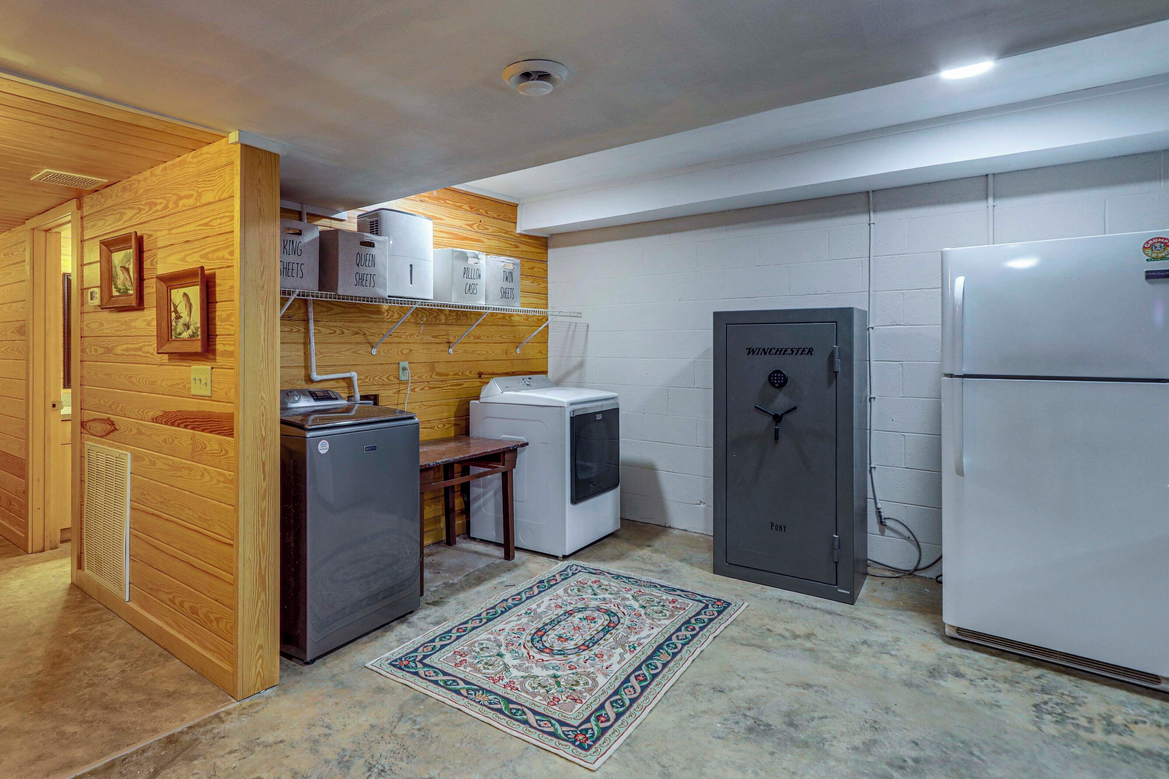 A compact kitchen with wooden paneling, a refrigerator, a washing machine, and a Winchester safe.