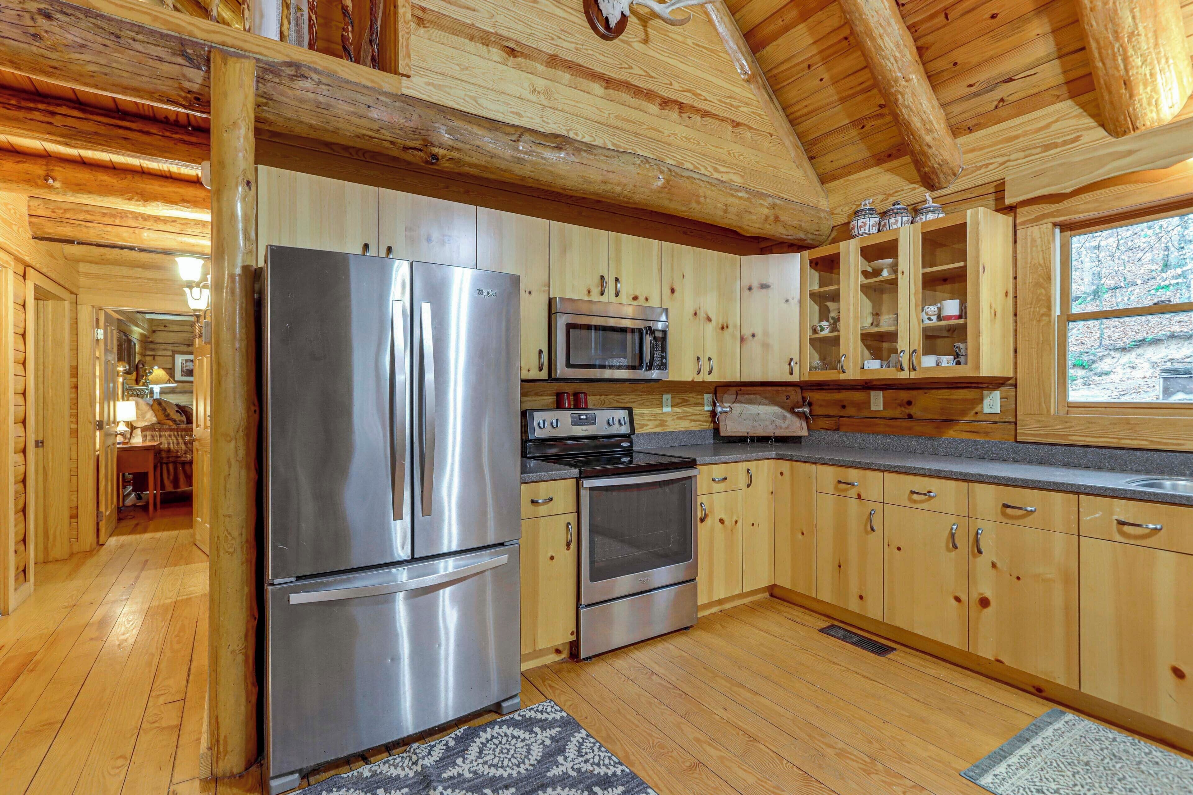 Interior de una cabaña de madera con cocina equipada con refrigerador, microondas, horno y armarios de madera.