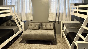 A room with bunk beds, a sofa, and an air conditioning unit. - Lovely 2-bedroom villa with pool & AC in Combate Beach, Boquerón Puerto Rico. (Cabo Rojo)