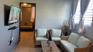A living room with a television, two sofas, a coffee table, and a ceiling fan. - Lovely 2-bedroom villa with pool & AC in Combate Beach, Boquerón Puerto Rico. (Cabo Rojo)