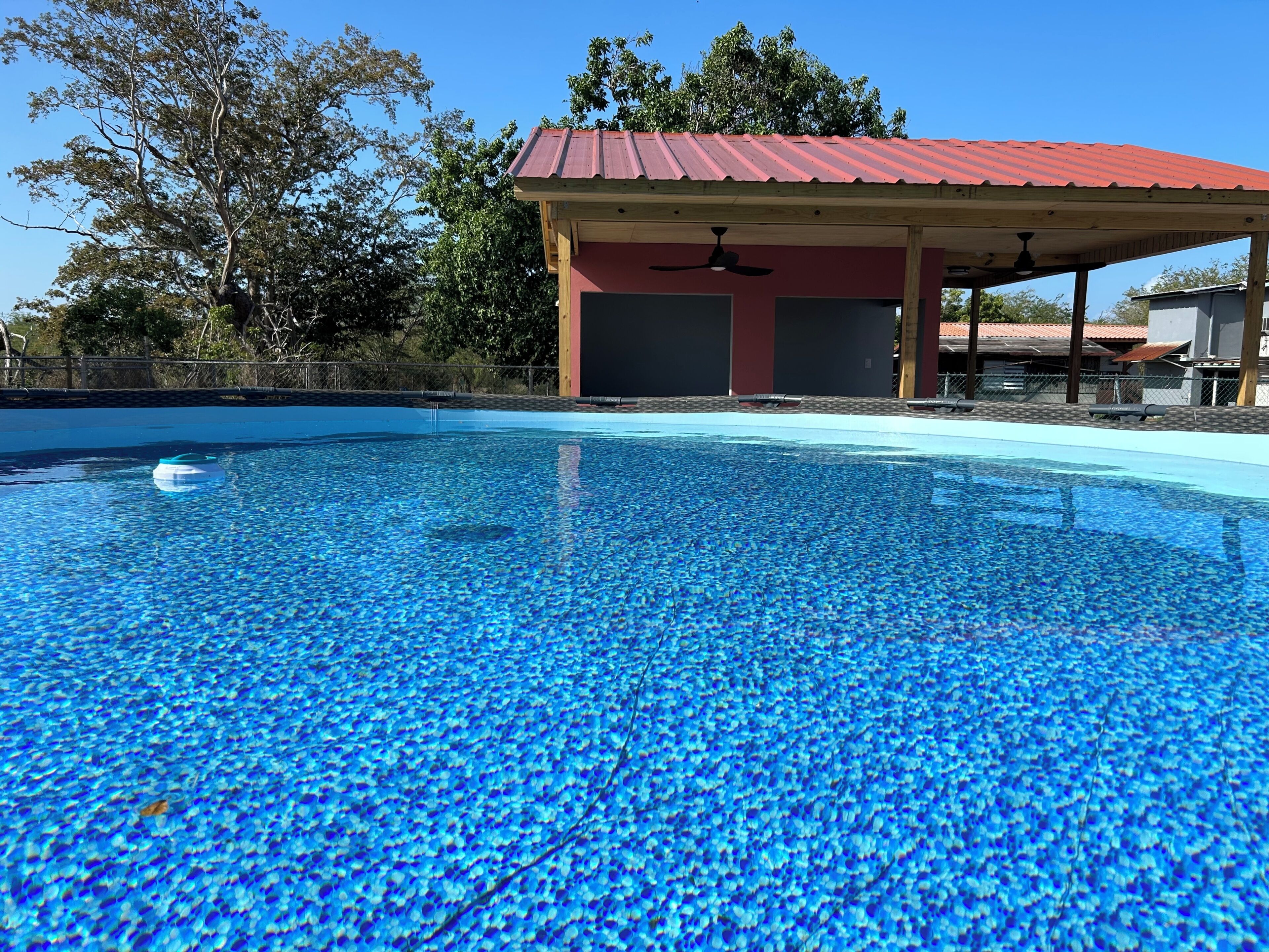 Ein Schwimmbecken mit einem Pavillon mit rotem Dach im Hintergrund.
