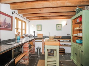 A kitchen with a wooden ceiling, a brick backsplash, and a green cabinet. - Bell House Cottage (Craven Arms)