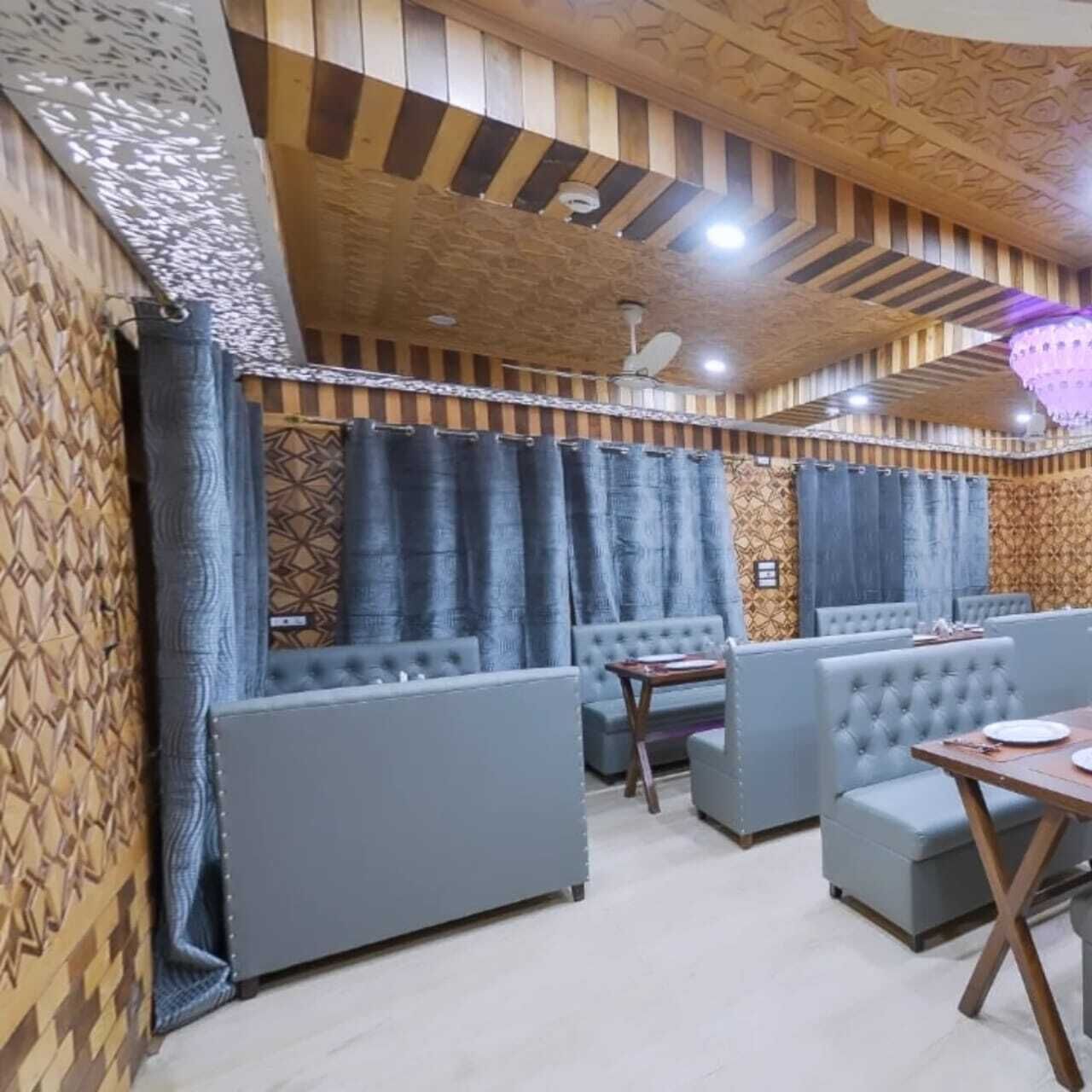 A restaurant with cushioned seating, patterned walls, and a wooden ceiling.