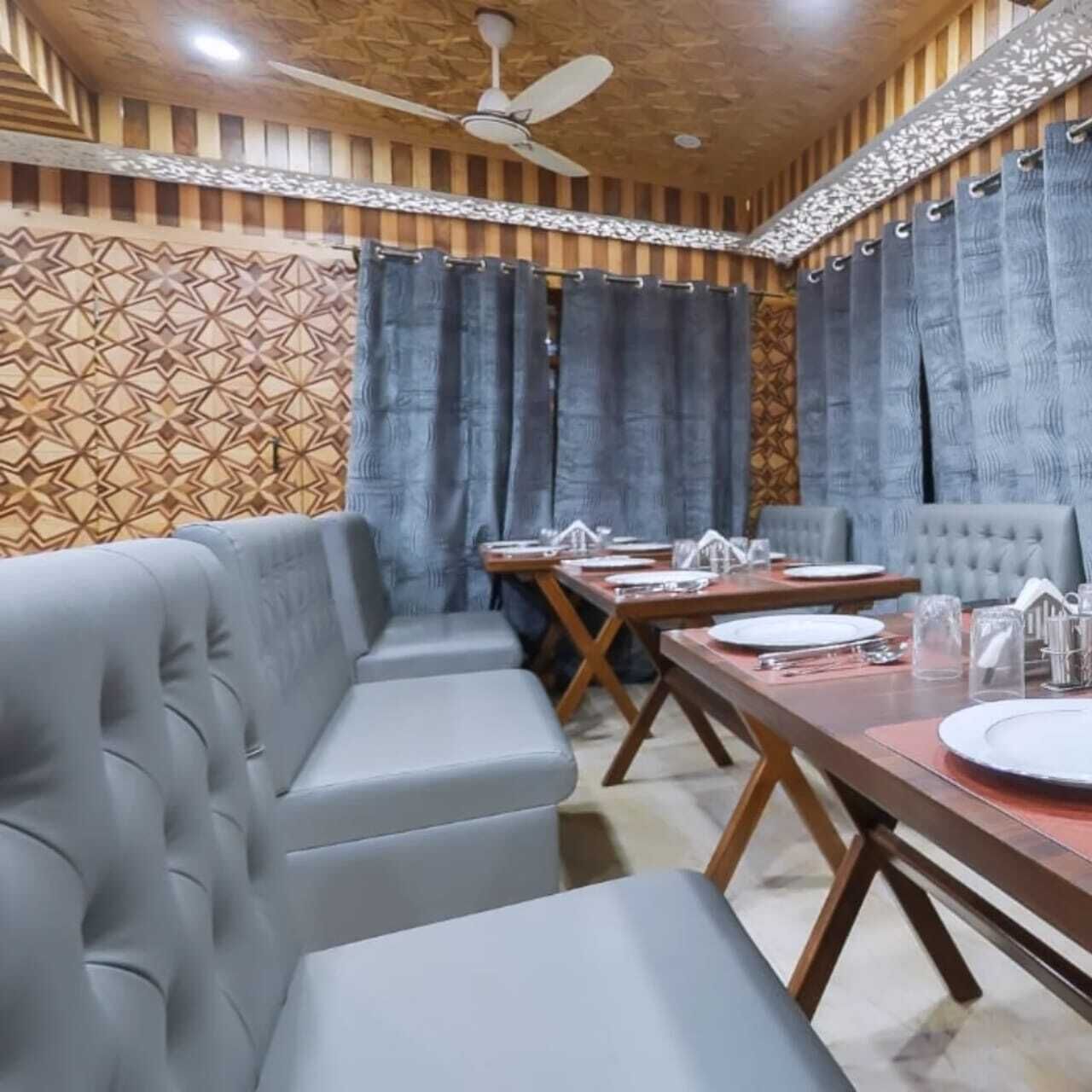 A dining area with a long table, cushioned seating, and a ceiling fan.