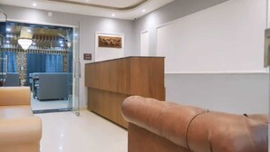 A modern hotel lobby with a reception desk, seating area, and a glass partition. - Hotel Your Hive (Srinagar)