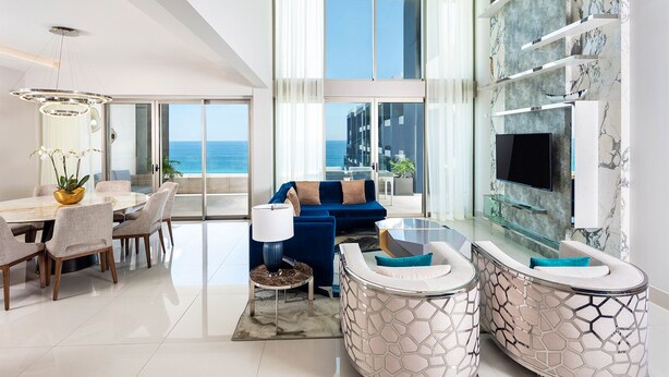 A modern living room with a large window, a sofa, a coffee table, and a dining area with chairs. - Spacious 3-bedroom condo with AC in enchanting Cancún (Cancún)