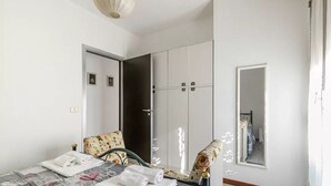 A bedroom with a bed, a chair, a wardrobe, and a mirror. - GuestHost - Rimini Gelsomino Huge Apartment (Rimini)