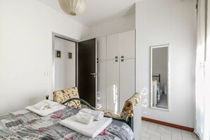 Ein Schlafzimmer mit einem Bett, einem Sessel, einem Kleiderschrank und einem Spiegel.