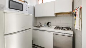 A compact kitchen with a microwave, stove, sink, and white cabinets. - GuestHost - Rimini Gelsomino Huge Apartment (Rimini)