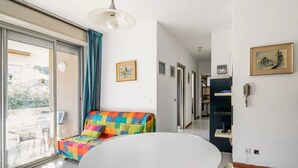 A room with a round table, a colorful sofa, a large window, and a door leading to a balcony. - GuestHost - Rimini Gelsomino Huge Apartment (Rimini)