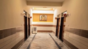 A hotel hallway with a marble floor, doors, and a wall-mounted artwork. - Shri Ved Vrinda Dham Aashram (Vrindavan)