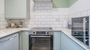 A kitchen with white subway tiles, a built-in oven, a stove, and a coffee machine.
