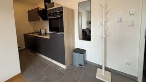A modern kitchen with a built-in oven, a sink, and a countertop. There is a trash bin and a mirror on the wall. - Simon Living - Apartment Pyramide central and quiet location in Karlsruhe (Karlsruhe)