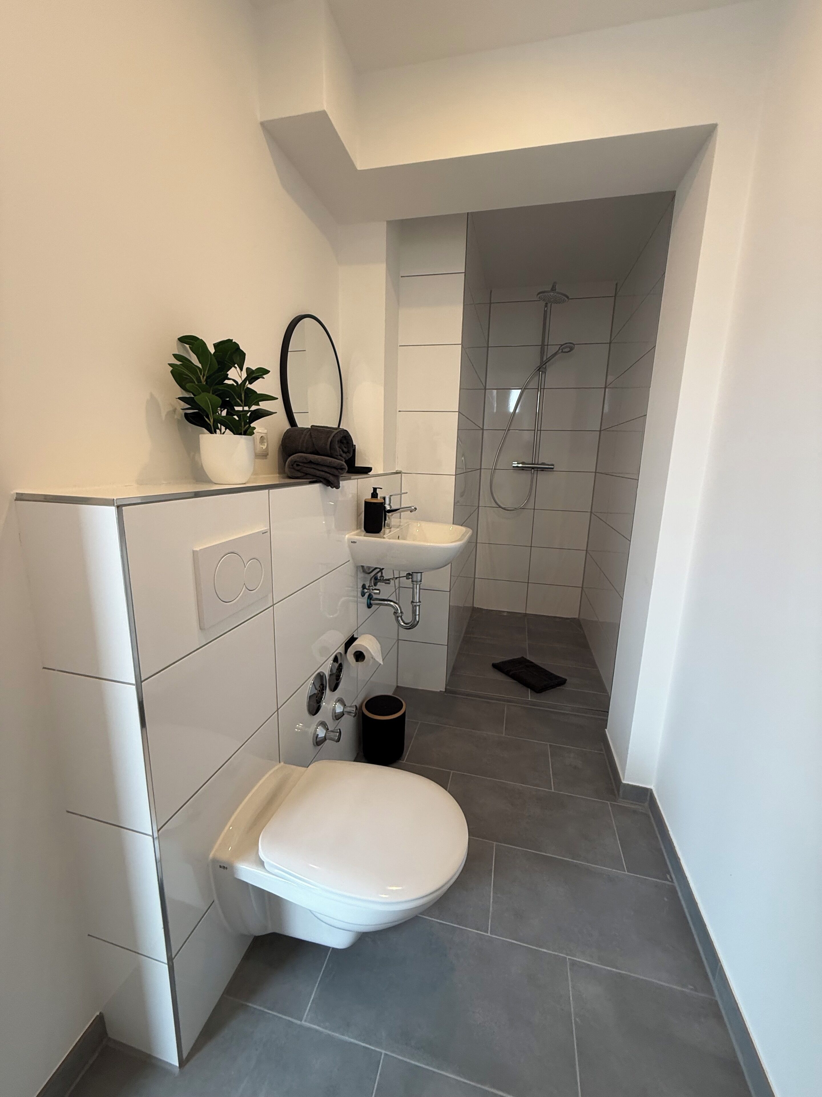 Une salle de bain moderne équipée de toilettes, d’un lavabo et d’une douche.