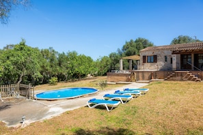 A swimming pool with lounge chairs, a stone building with a tiled roof, and a wooden fence. - Holiday Home 'Enjoy Finca Son Galiana' with Private Pool, Wi-Fi and Air Conditioning (Illes Balears)