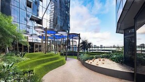 Un bâtiment moderne doté de grandes fenêtres en verre réfléchissant, d’un cheminement incurvé et d’un espace paysager avec de la pelouse verdoyante et des plantes.