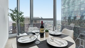Une table à manger dressée avec des assiettes, des couverts et des verres à vin, une bouteille de vin et une petite plante posée sur la table.