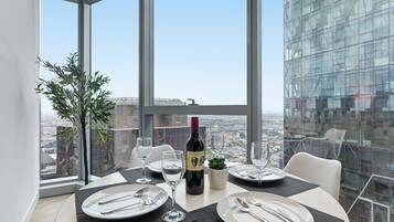 A dining table set with plates, cutlery, and wine glasses, with a bottle of wine and a small plant on the table.