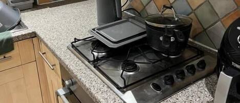 Una cocina equipada con estufa a gas, hervidor, tostadora y refrigerador.