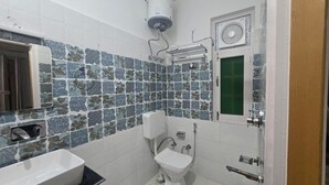 Baño con lavamanos, inodoro y ducha blancos.
