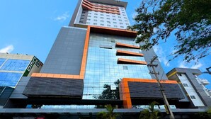 A modern building with a glass facade, a prominent orange and grey color scheme, and a visible entrance area with a sign. - NORD LUXXOR CITYMIX (Campina Grande)