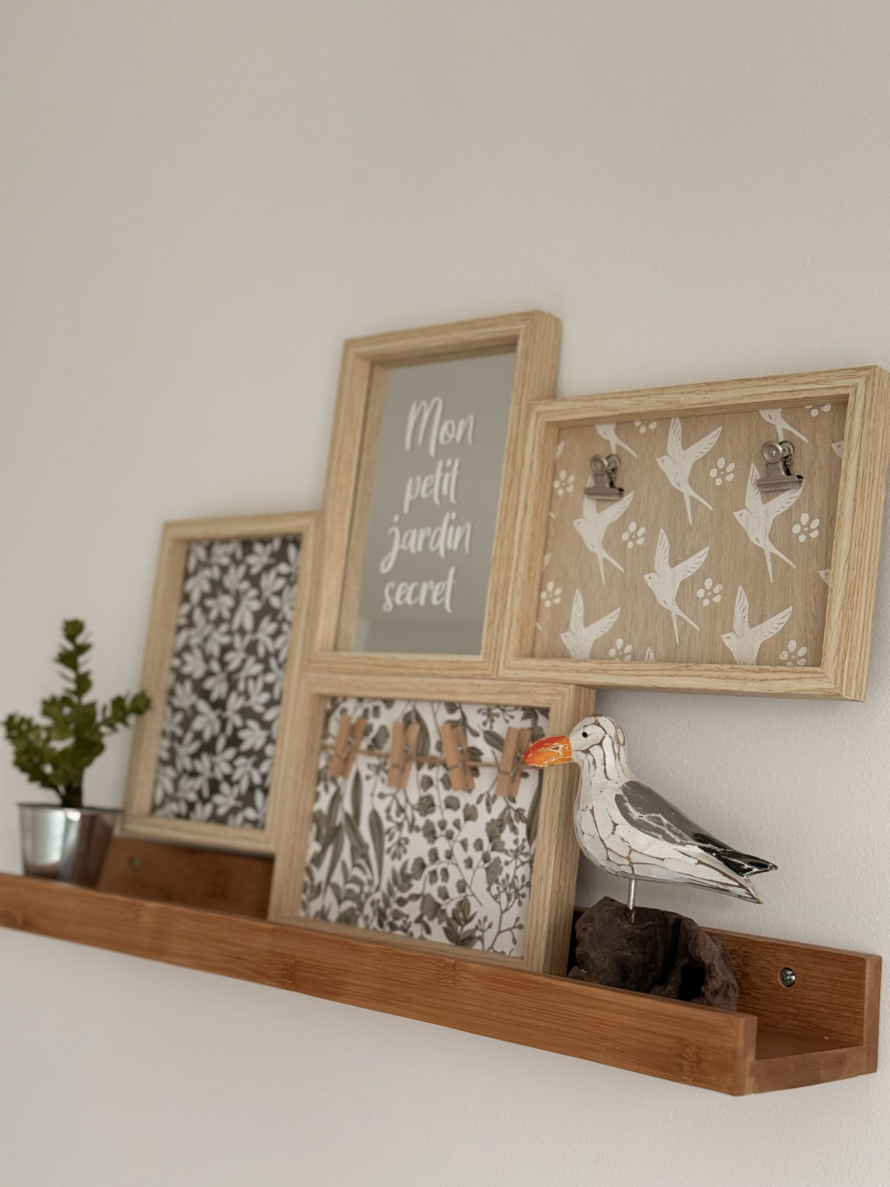 Una estantería de madera con tres cuadros enmarcados y un pájaro decorativo.