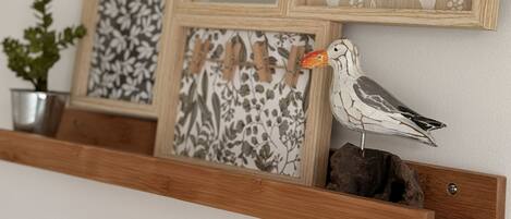 Una estantería de madera con tres cuadros enmarcados y un pájaro decorativo.