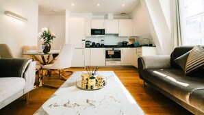 A modern living room with a marble coffee table, a sofa, a dining table with chairs, and a kitchen in the background. - LUX Bloomsbury Flat By Holborn Covent Garden (London)
