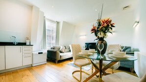 A modern kitchen with a dining area, white cabinetry, and a glass table. - LUX Bloomsbury Flat By Holborn Covent Garden (London)
