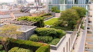 A rooftop garden with a variety of plants and a modern building with large windows. - LUX Aldgate Apartment I Central London Zone 1 (London)