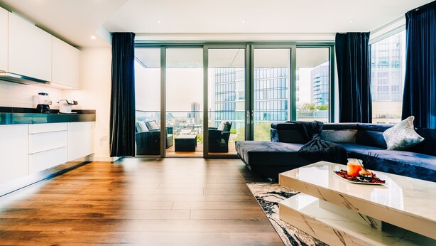 A modern living room with a sofa, coffee table, and a view of the city through large windows. - LUX Aldgate Apartment I Central London Zone 1 (London)